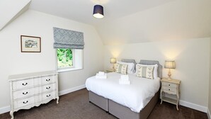 Un dormitorio con cama, mesitas de noche, cómoda, ventana con vistas y luz de techo.