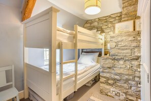 A bunk bed in a room with a stone wall and a window. - 3 Bed in Swanage (oc-dc052) (Worth Matravers)