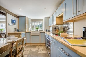 A kitchen with a dining area, a window with a view, and a coffee machine. - 3 Bed in Swanage (oc-dc052) (Worth Matravers)