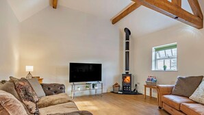 A living room with a fireplace, leather sofas, a TV, and wooden beams. - 3 Bed in Ashbourne (oc-94309) (Waldley)
