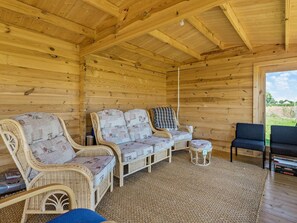 En inredning med träpanel och möbler i rotting, en soffa och ett litet bord.