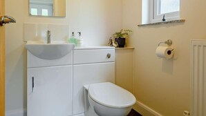 Un baño con un lavamanos blanco, un inodoro y una ventana sobre el inodoro.
