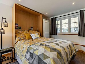 A bedroom with a bed, a wooden headboard, a window with curtains, a bedside table, and a floor lamp. - 1 Bed in Launceston (oc-86675) (South Petherwin)