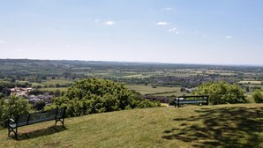 A bench on a grassy hill overlooking a valley with houses and fields. - 1 Bed in Wotton-under-edge (oc-91936) (Wotton-under-Edge)