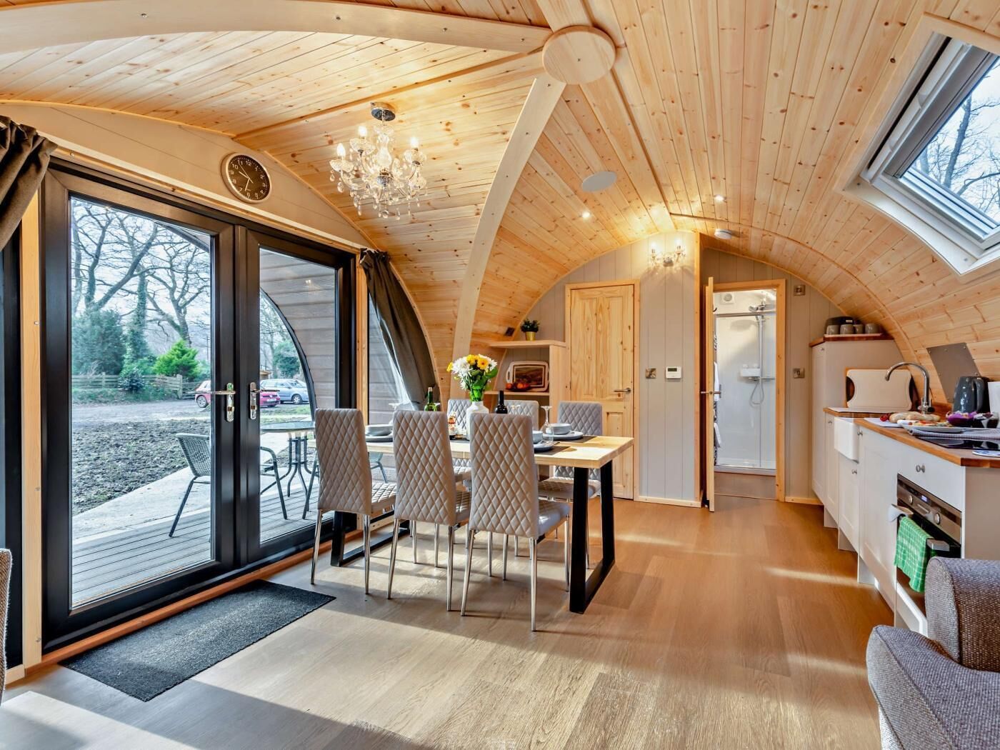 Un intérieur de chalet chaleureux comprenant un coin repas, une cuisine et de grandes portes-fenêtres coulissantes.