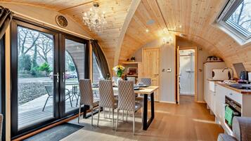 Un intérieur de chalet chaleureux comprenant un coin repas, une cuisine et de grandes portes-fenêtres coulissantes.