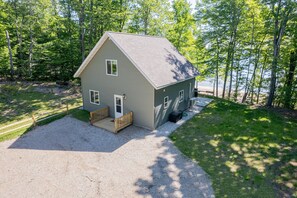 Une maison de plain-pied avec une allée en gravier, une terrasse en bois et un petit porche.