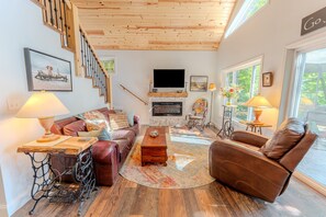 A living room with a fireplace, a sofa, a recliner, a coffee table, and a staircase.
