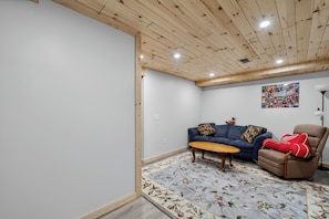 Ein Zimmer mit Holzboden, einem blauen Sofa, einem braunen Sessel und einem Teppich mit Blumenmuster.