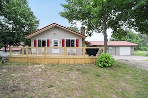 A single-story house with a red roof and white siding, a fenced deck, and a small bush in the front yard. - Gaylord Lodge:  Forest Escape: Golf, Ski, Fish and Sleep 8! (Gaylord)