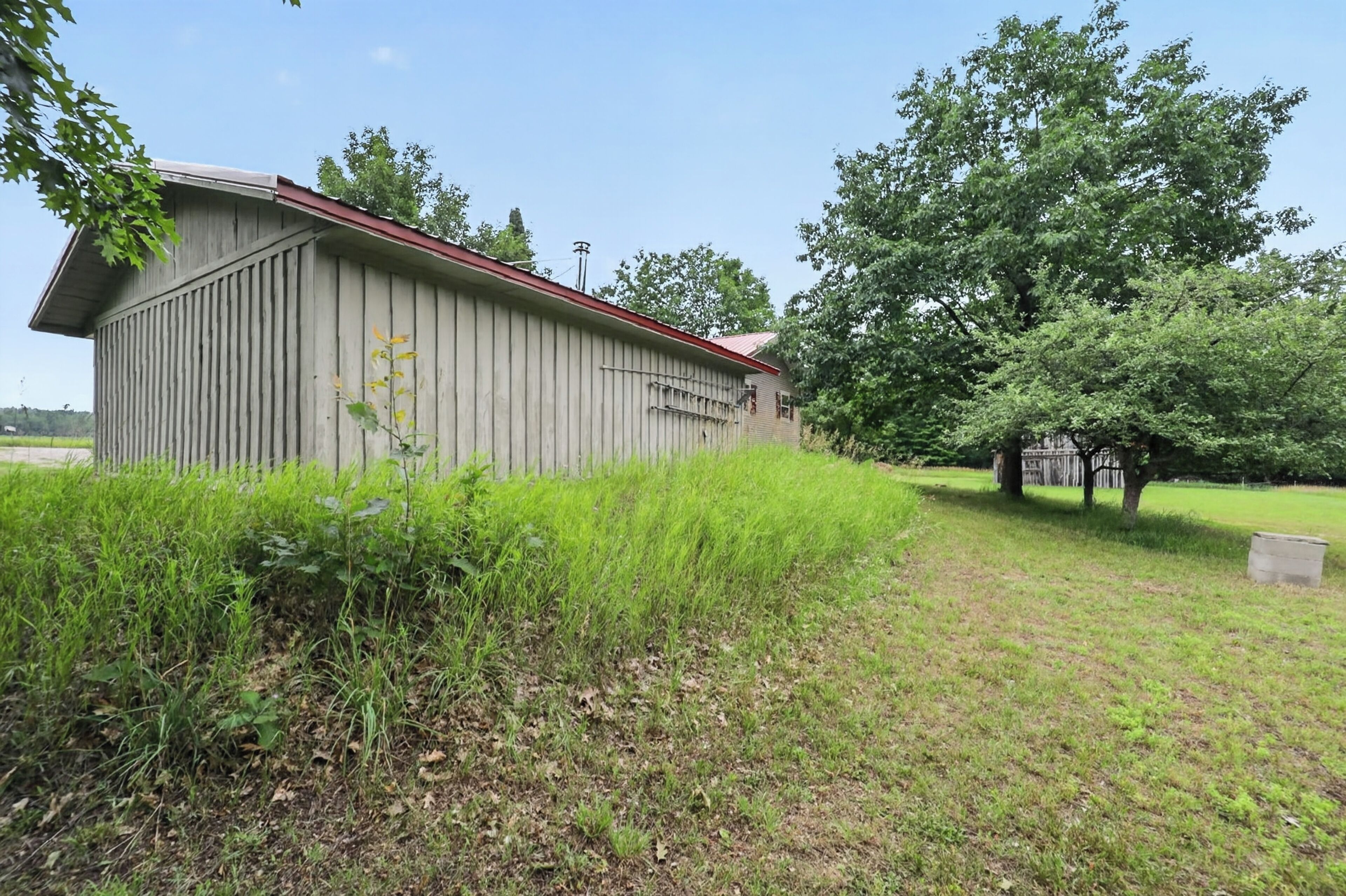 A large, single-story building with a red roof, surrounded by grass and trees.