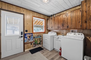A laundry room with wooden walls, a white door, and two white appliances. - Gaylord Lodge:  Fall Color Getaway | Gaylord | 4BR Forest Retreat | Sleeps 8 (Gaylord)