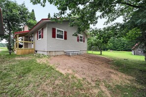 A single-story house with a red front door and windows, surrounded by a grassy yard and trees. - Gaylord Lodge:  Forest Escape: Golf, Ski, Fish and Sleep 8! (Gaylord)