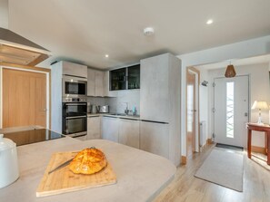 Eine moderne Küche mit Edelstahlgeräten, einem Holzer Schneidebrett mit Messer und einem Essbereich mit einer Lampe.