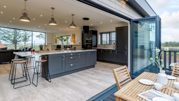 A modern kitchen with a large island, bar stools, and pendant lighting. - 3 Bed in Belford (oc-78058) (Easington)