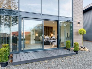 Una casa moderna con un amplio ventanal que da a un dormitorio con cama y una silla.