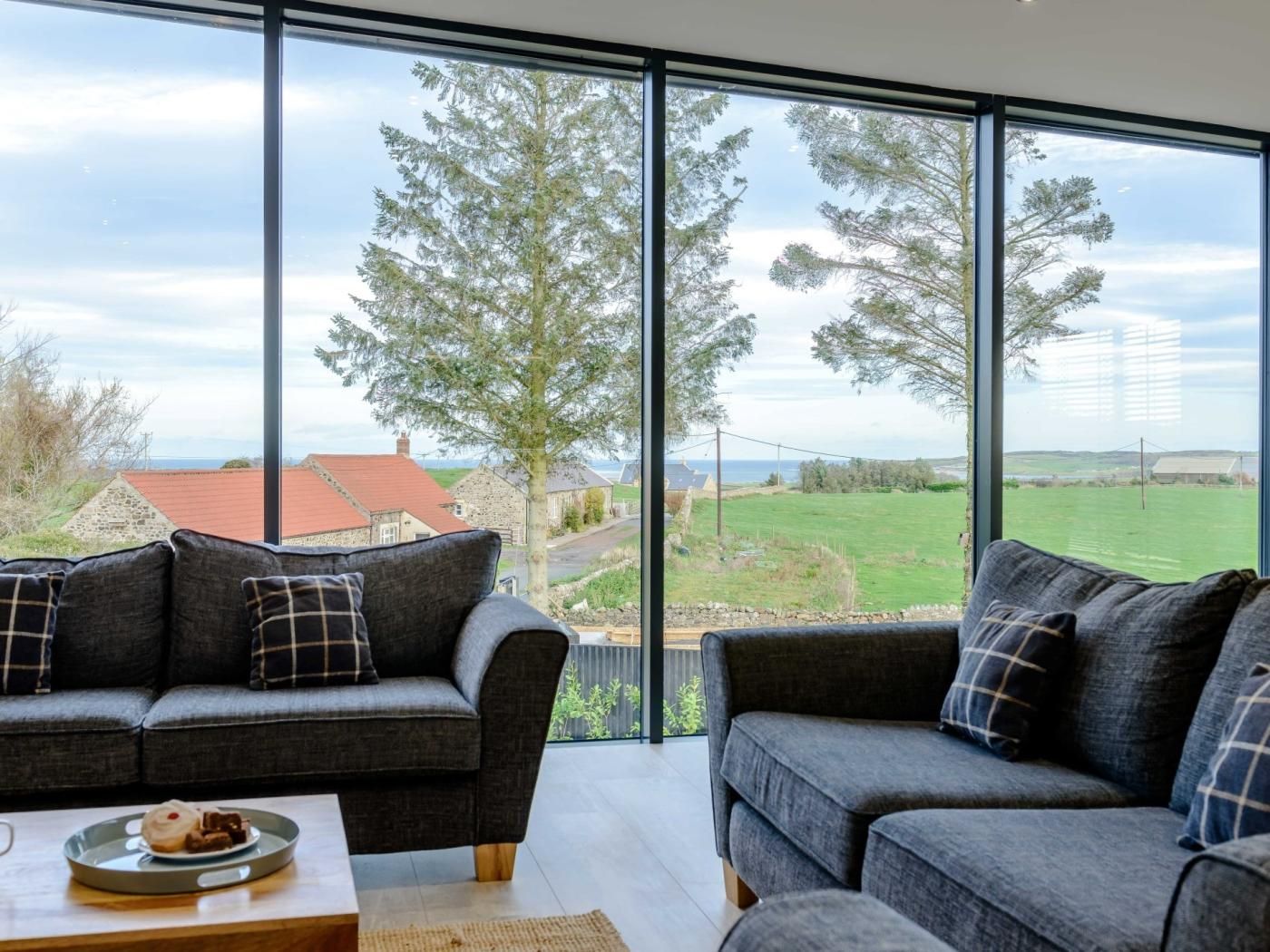 A modern living room with a large window overlooking a rural landscape.