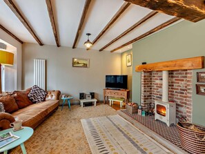 Ein gemütliches Wohnzimmer mit Sofa, Fernseher, Kamin und einem gemusterten Teppich.