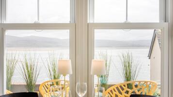 A table set for two with chairs, a view of a body of water, and a building in the background.