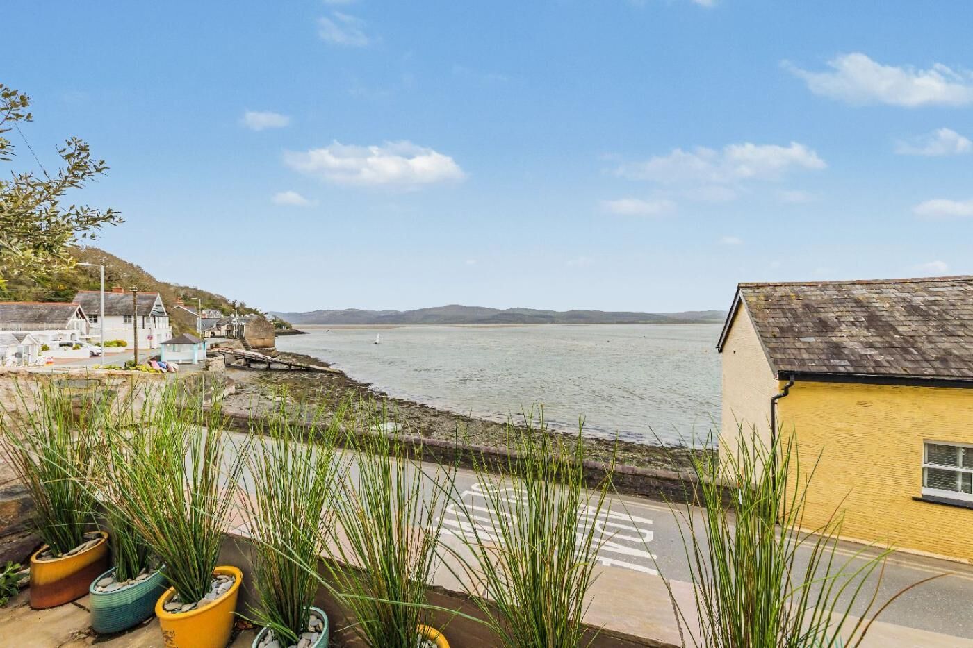 A coastal view with a building, a body of water, and distant hills.