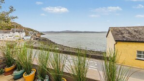 A coastal view with a building, a body of water, and distant hills. - 2 Bed in Aberdyfi (oc-dy020) (Aberdovey)