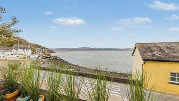 A coastal view with a building, a body of water, and distant hills.