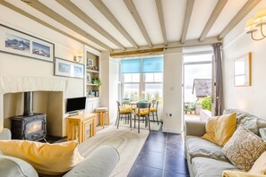 A cozy living room with a fireplace, a television, a dining area with chairs, and a sofa. - 2 Bed in Aberdyfi (oc-dy020) (Aberdovey)