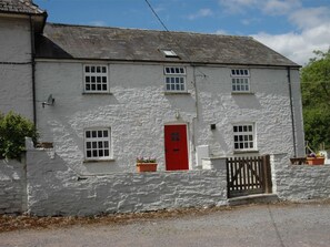 A two-story white building with a red door, multiple windows, and a gated entrance. - 2 Bed in Brecon (oc-bn073) (Cradoc)