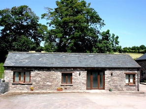 A stone building with a sloped roof, two windows with wooden frames, and a door with glass panels. - 2 Bed in Cradoc (BN103) (Cradoc)