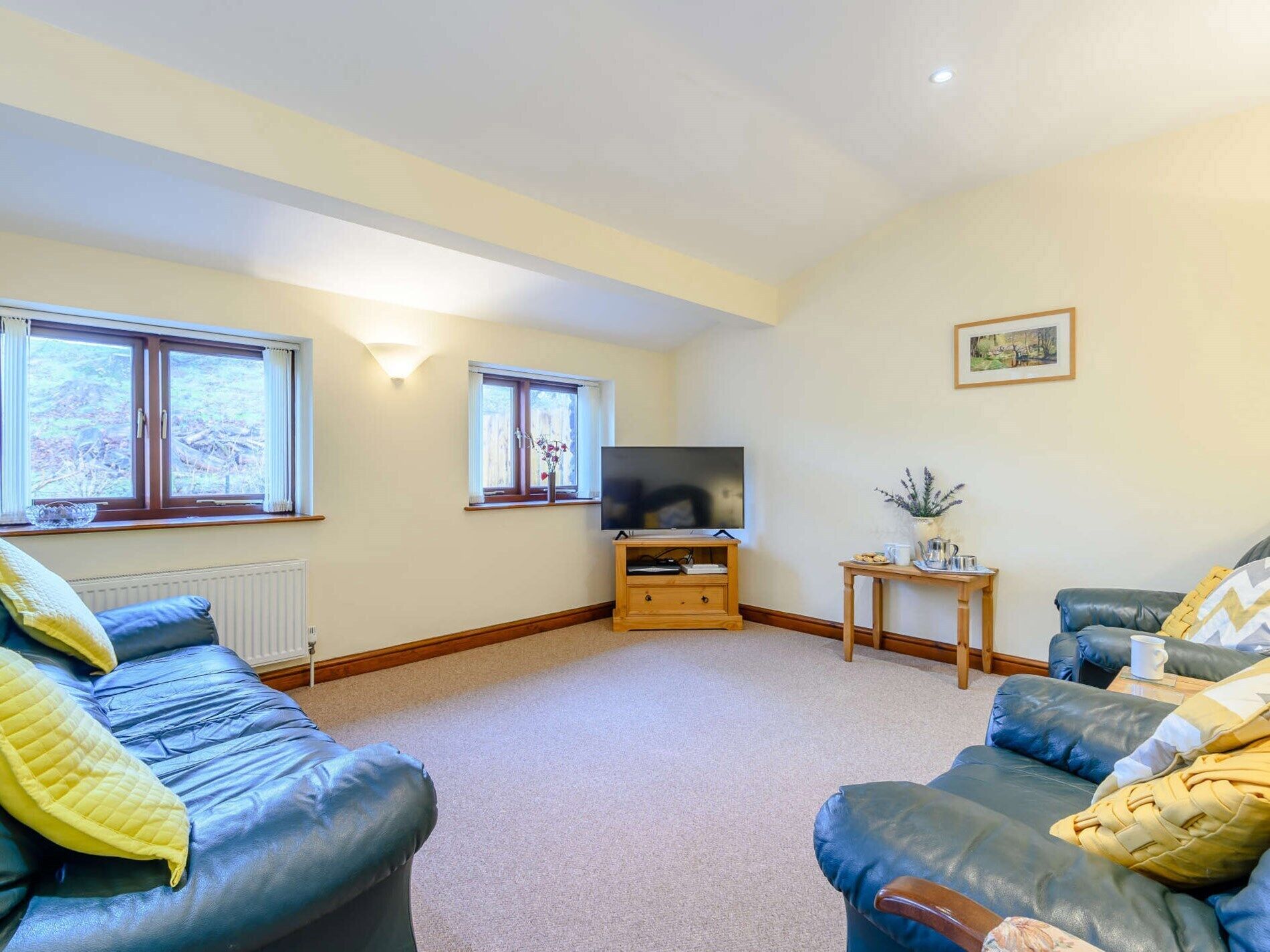 A living room with two sofas, a television, and a small table with a vase.