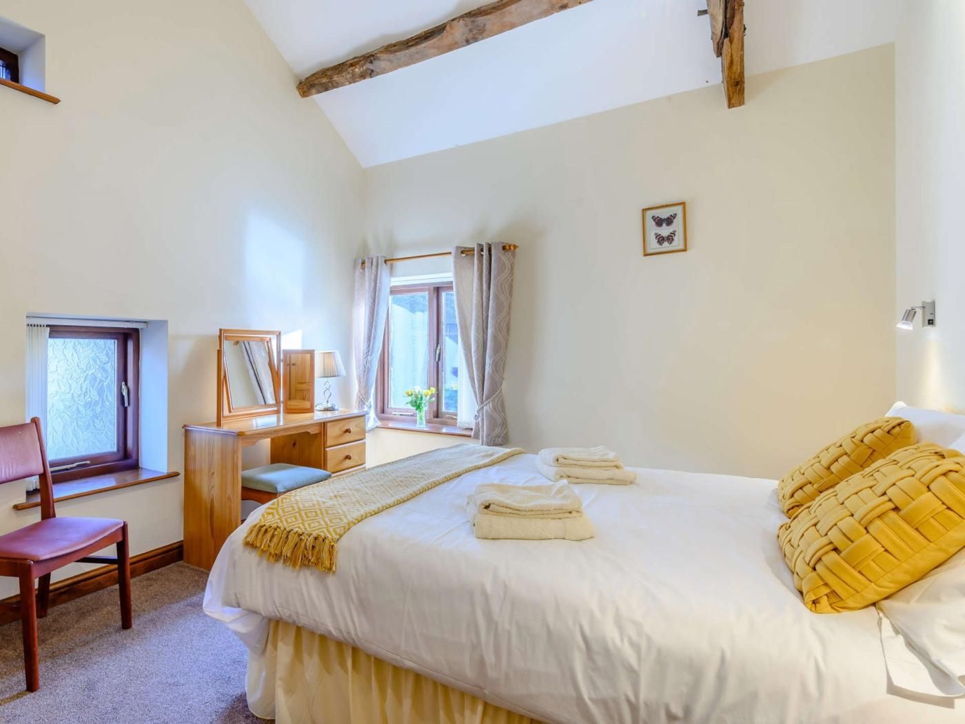 Une chambre à coucher avec un lit, un bureau, une chaise et une fenêtre avec des rideaux.