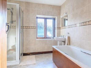 Un baño con cabina de ducha de vidrio, una ventana, un lavabo y una bañera.