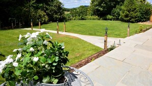 Ein angelegter Garten mit gepflastertem Weg, einem Blumentopf mit weißen Blüten und einer Laterne.