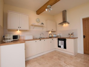 A kitchen with white cabinets, a microwave, a kettle, and a toaster.