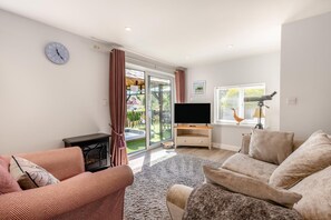 A living room with a television, sofa, and a fireplace. - 1 Bed in Paignton (oc-55119) (Paignton)