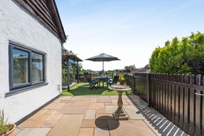 Eine Terrasse mit Tisch und Stühlen, einem Vogelbad und einem Holzzaun.