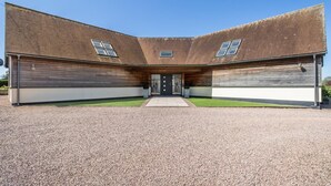 Un bâtiment moderne à l’architecture symétrique, doté d’une entrée centrale, de deux ailes latérales et d’une allée gravillonnée.