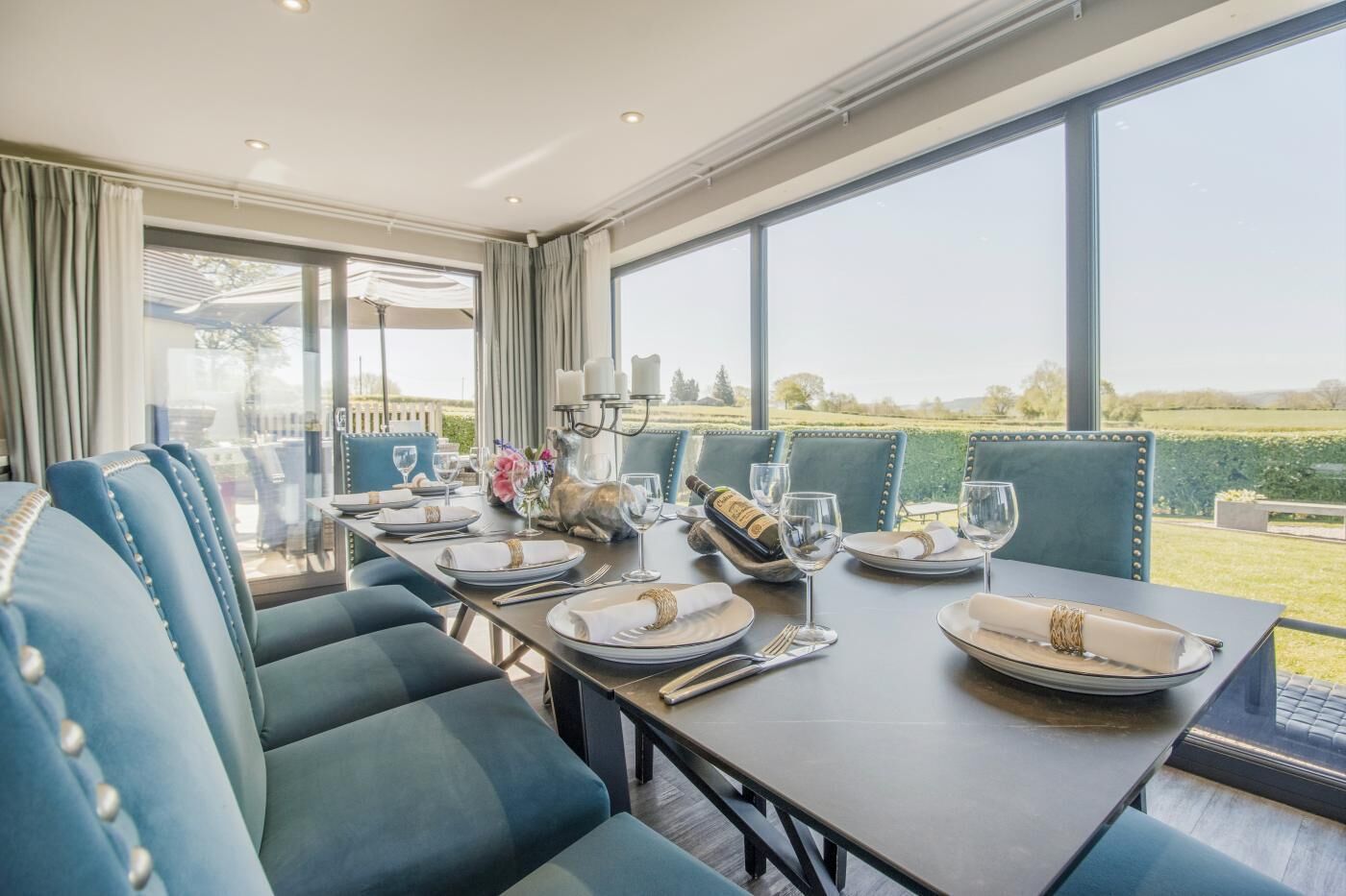 A dining area with a table set for four, large windows, and a view of the outdoors.
