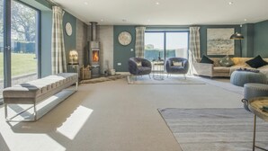 Un salon spacieux doté d’une cheminée, de grandes fenêtres et offrant une vue sur l’extérieur.