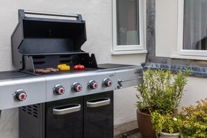 Ein Grill mit vier Brennern, einer Bedienblende und einem Schornstein.