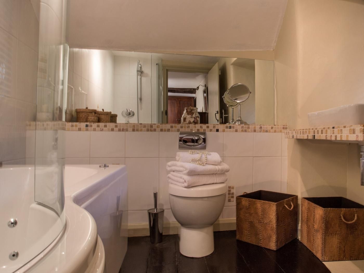 A bathroom with a bathtub, toilet, and a mirror.