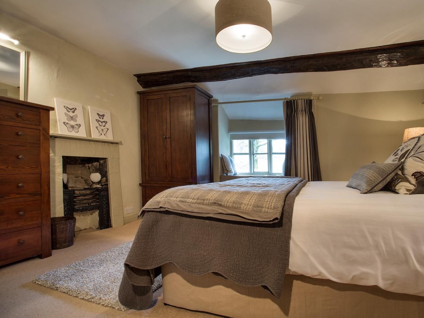 Une chambre à coucher avec un lit, une armoire, une cheminée et une fenêtre avec des rideaux.