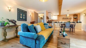 A living room with a sofa, coffee table, and dining area with chairs and a table. - 1 Bed in Barnstaple (oc-93422) (Prixford)