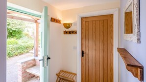 A wooden door with a light fixture above it, a small wooden bench, and a brick wall. - 1 Bed in Barnstaple (oc-93422) (Prixford)