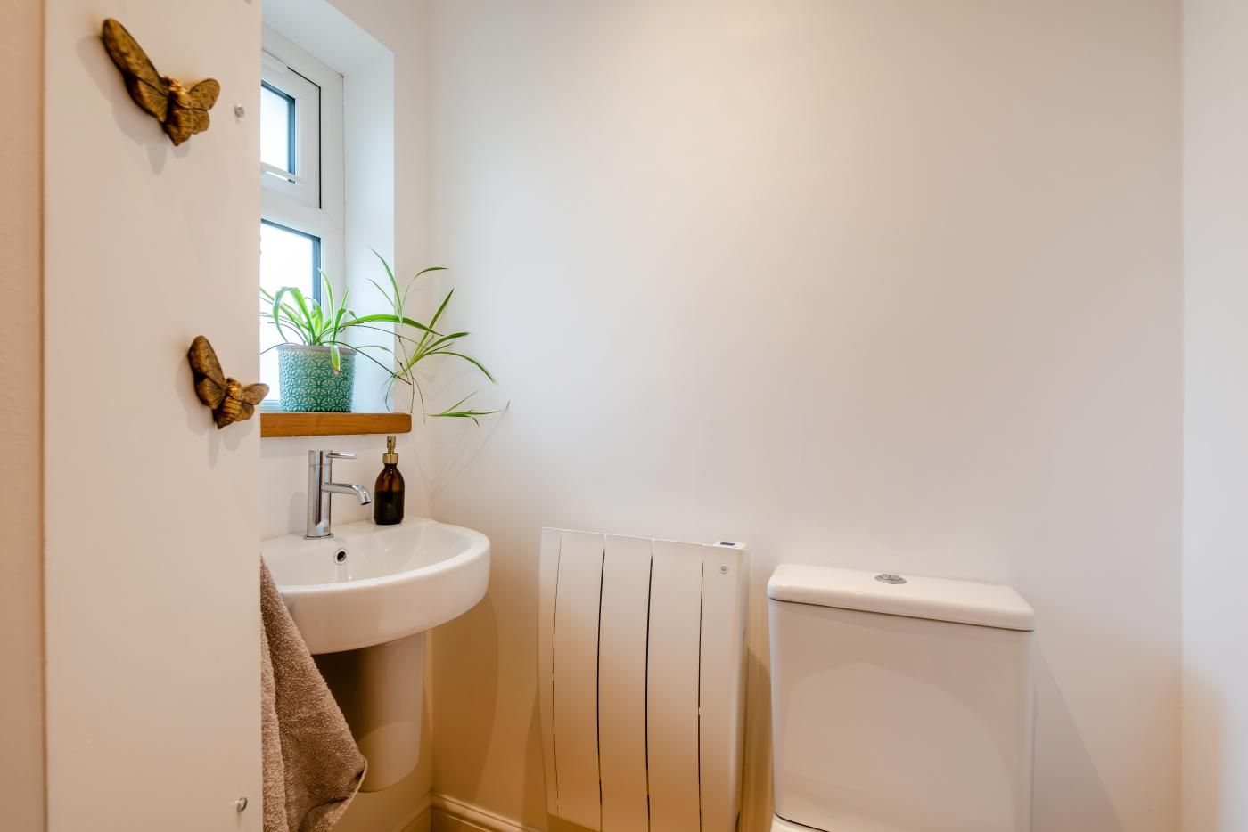 A bathroom with a white sink, a mirror, a towel, a radiator, and a toilet.
