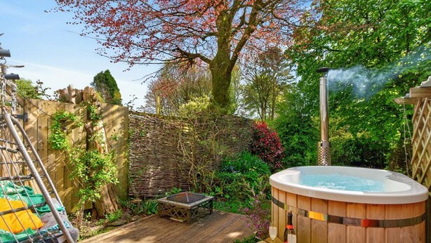 A hot tub in a garden with a wooden deck, a swing, and a fence. - 1 Bed in Barnstaple (oc-93422) (Prixford)