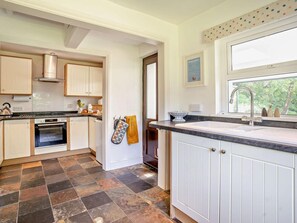 A modern kitchen with white cabinetry, a black tiled floor, and a window providing a view of the outdoors.