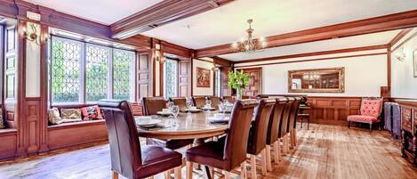 A spacious dining room with a long wooden table, multiple chairs, and a bench along the wall.