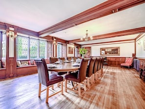 A spacious dining room with a long wooden table, multiple chairs, and a bench along the wall.