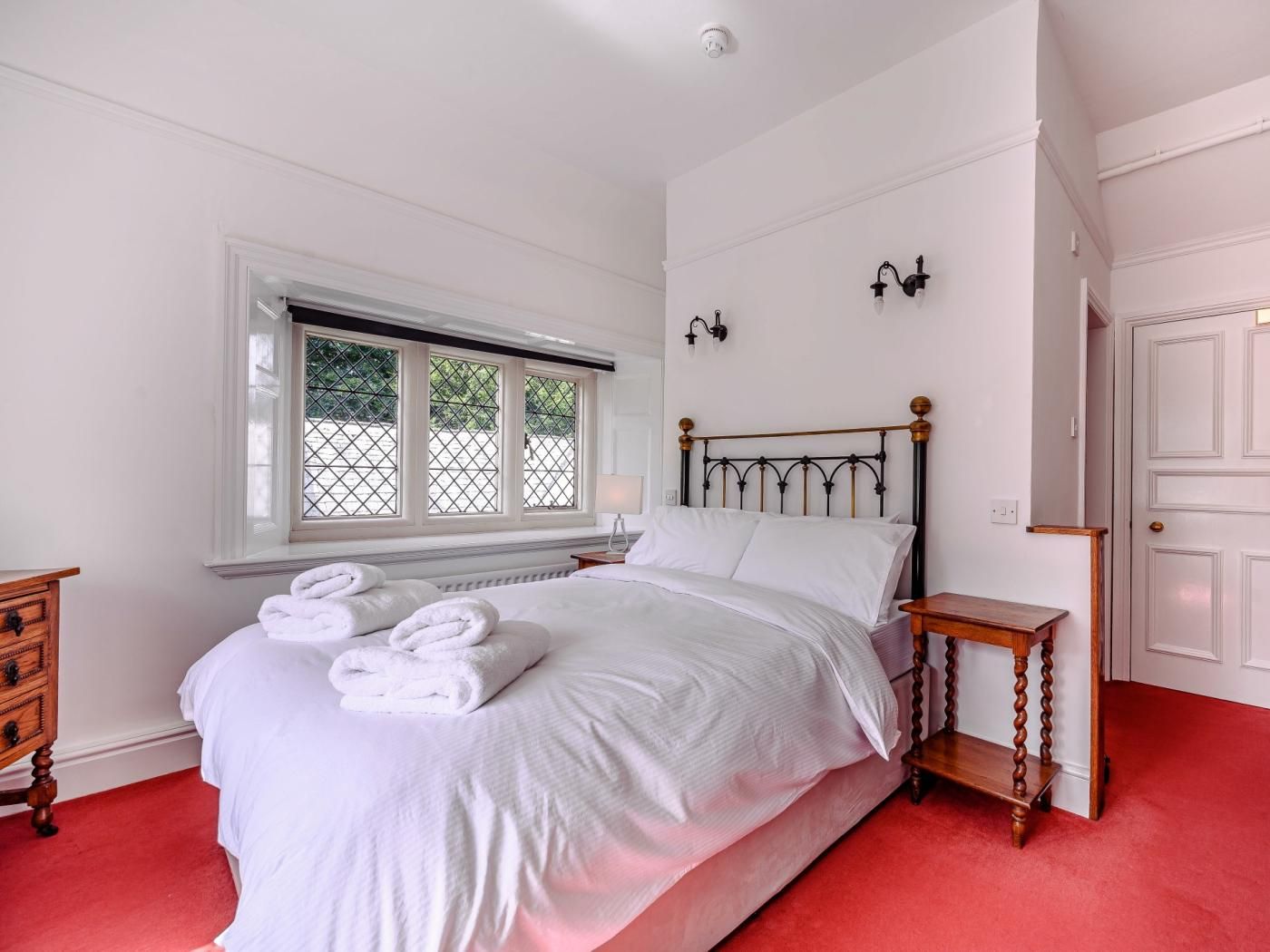 A bedroom with a bed, a window, a nightstand, a dresser, and a door.